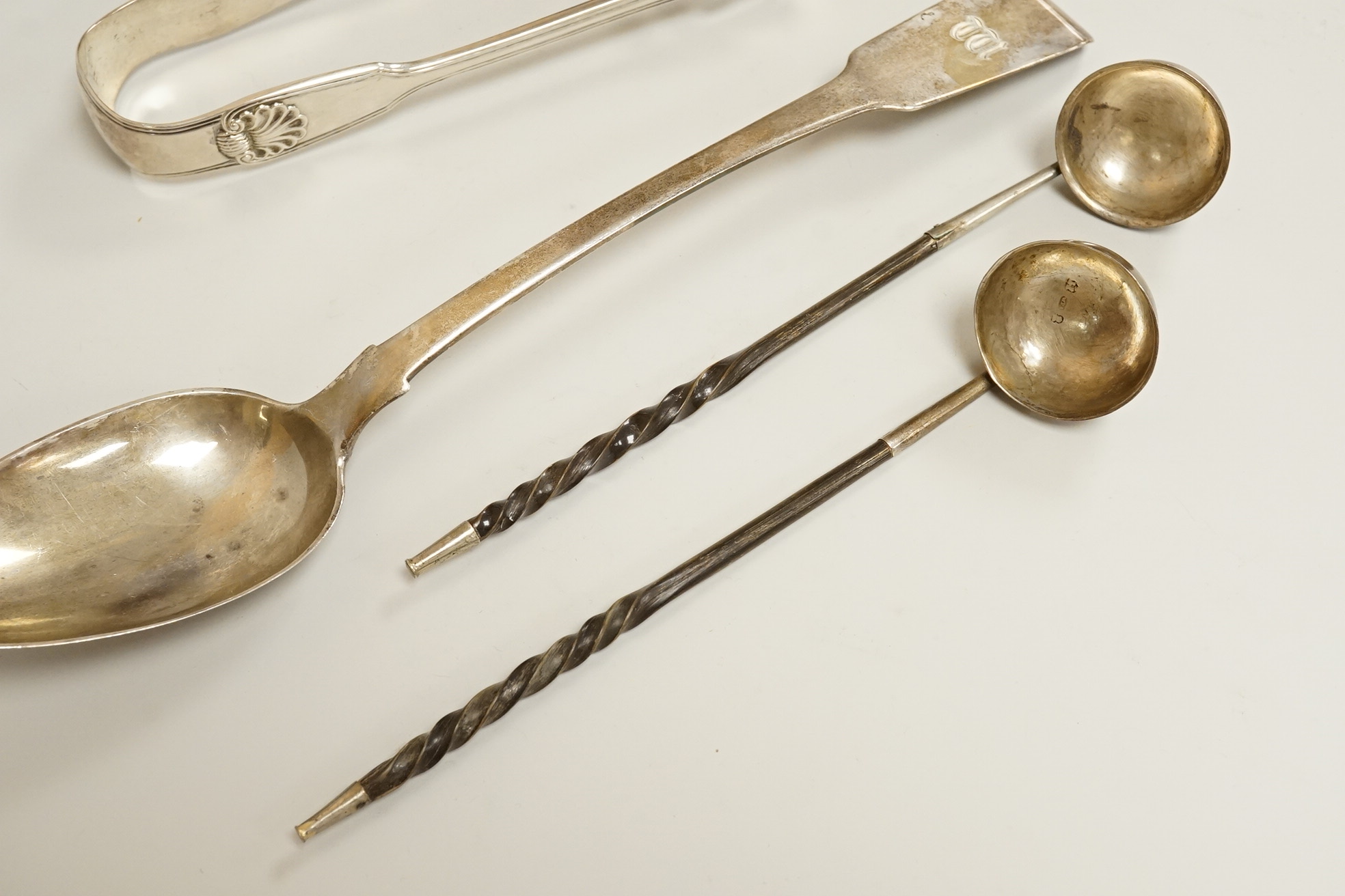 A pair of William IV silver fiddle, thread and shall pattern asparagus servers, a George IV silver fiddle pattern basting spoon, Robert Gainsford, Sheffield, 1826, 31.2cm, 10.8oz and two 19th century white metal toddy la